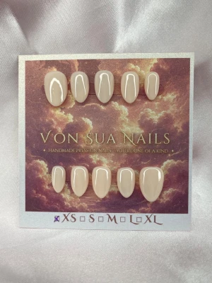 Nude press-on naglar almond XS - Handgjorda press-on nails i en mjuk nude-beige nyans med glansig finish. En stilren och minimalistisk design som passar till allt.  Form: Extra Short Almond Storlek: XS 10 naglar ingår