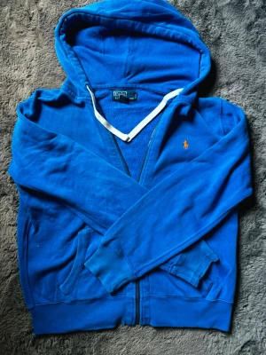 Ralph Lauren Zip Hoodie  - Hej, Säljer en snygg och klassisk Polo Ralph Lauren zip hoodie i en riktigt fin klarblå färg med orange broderad logga. Mjuk och skön med fleecefodrad insida, perfekt året runt.  