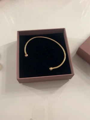 Guldigt öppet armband med kulor - Säljer ett fint guldigt armband. Köpt i ett klockset men aldrig kommit till användning💓💓Postar samma dag!