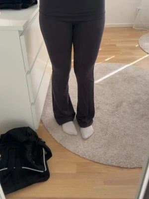 Mörkgrå bootcut yogabyxor - Säljer ett par mörkgrå yogabyxor med bootcut-modell och bred linning. Byxorna är stretchiga och bekväma, perfekta för chill eller träning. Materialet känns mjukt och följsamt mot kroppen. Passar dig som gillar en avslappnad men ändå snygg stil.