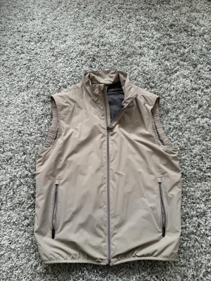 Beige väst från Mango  - Stilren beige väst från mango i ett extremt najs matrial perfekt för utomhus aktivitet men även golf eller ha som en stilren väst! Skicket är extremt bra!