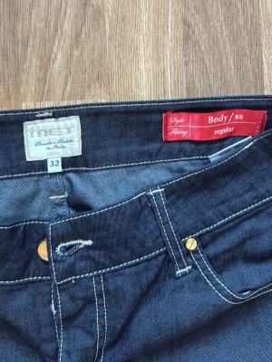 Mörkblå regular jeans från MET - Snygga mörkblå jeans från MET i regular fit. Klassisk femficksmodell med kontrastsömmar och raka ben. Jeansen har gylf med knapp och dragkedja samt coola detaljer på bakfickorna. Perfekta för en avslappnad och trendig look.