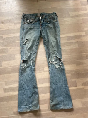 Blå slitna true religion jeans - Säljer dessa true religion jeans då dom inte passar längre men älskar dom har tre hål på benen och är lite slitna där bak men anars i bra skick, dom har  36 i midjemått och inerbenslängden är 82❤️