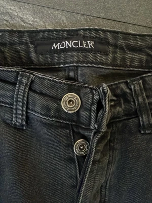Svart/gråa jeans  - Snygga svarta jeans med distressed detaljer och slitningar framtill. Jeansen har raka ben, klassisk femficksmodell och silverfärgade knappar. Materialet är denim med en tvättade look som ger en cool vibe.