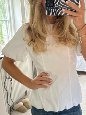 Vit figursydd blus med puffärm - Superfin figursydd blus från ginatricot i storlek 38. Endast använd ett fåtal gånger då den är lite stor på mig!