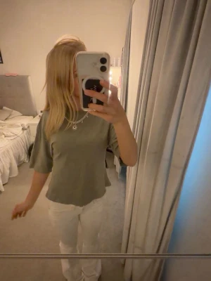 Grön kortärmad topp - En enkel grön topp med korta ärmar och rak passform. Toppen har en mjuk känsla och passar perfekt till både jeans och kjol. Färgen är dovt grön och modellen är klassisk utan synliga detaljer eller mönster.