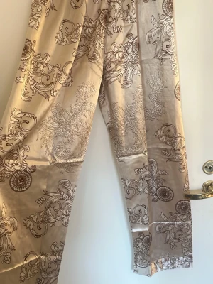 Beige satinpajamasbyxor  - Säljer ett par beige satinpajamasbyxor i storlek XS/S som är köpt i Hongkong. Användt en gång 