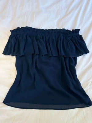 Mörkblå / Svart offshoulder volangtop - Snygg mörkblå offshoulder topp med volangdetalj upptill och tunna axelband som kan användas eller tas bort.