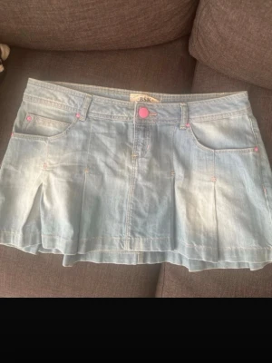 Y2k lågmidjad jeanskjol med volang - Super söt  ljusblå y2k jeans kjol med volanger. Den har rosa detaljer som verkligen ger det den där lilla extra. Köpt på vinted, super söt till sommaren men även till hösten.  Midjan:42   Längd:32💞 Skriv vid frågor eller om man vill diskutera pris