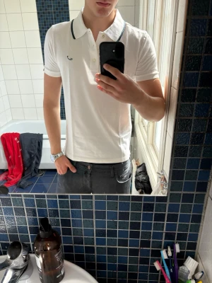 Vit pikéskjorta med svart kant - Klassisk vit pikétröja med svart kant på kragen och liten broderad logga på bröstet från Jacob Cohen. Väldigt stretchig och formar sig fint. Nypris 4000kr.