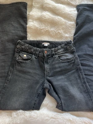 Grå jeans från Gina Tricot - Snygga grå jeans från Gina Tricot i storlek 170. Jeansen har klassisk femficksmodell, raka ben och detaljerade sömmar. Tillverkade i mjukt denimtyg med en cool tvättad look och knapp med logga framtill. Midwaist från Gina Young 
