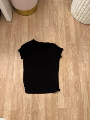 Svart basic t-shirt - En enkel svart t-shirt med korta ärmar och rund hals. Perfekt att matcha med jeans eller kjol för en clean och stilren look. Tillverkad i mjukt material som känns skönt mot huden.