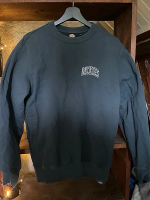 Sweatshirt från Dickies - Klassisk sweatshirt från Dickies med rund halsringning och ribbade muddar vid ärmslut och nederkant. Diskret Dickies-logga broderad på bröstet. Perfekt för en avslappnad och stilren look.