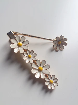 Hårspänne med blommor.  - Säljer ett gulligt hårspänne dekorerat med vitablommor i metall. 