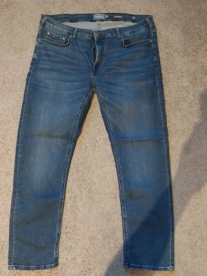 Blå raka jeans med dragkedja - Snygga blå jeans i klassisk modell med raka ben och dragkedjegylf. Jeansen har fem fickor och kontrastsömmar. Perfekta till en avslappnad stil och passar till det mesta. Materialet är denim i bomull.