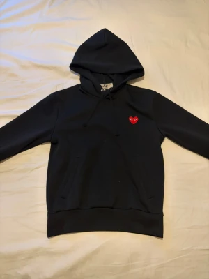 Comme des garçon hoddie - Säljer en svart Comme des garçon hoddie i storlek S. Den har används några gånger men inga skador förutom ett Vädligt litet märke i vänstra armen. skriv frågor som jag kan svara på!