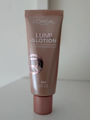 L'Oréal Lumi Glotion 902 Light Glow - Använd några gånger. L'Oréal Lumi Glotion i nyansen 902 Light Glow är en flytande highlighter som ger naturlig lyster till huden. Kommer i en beige-rosa tub med skruvlock och har en lätt, krämig formula som smälter in i huden för en fräsch glow.