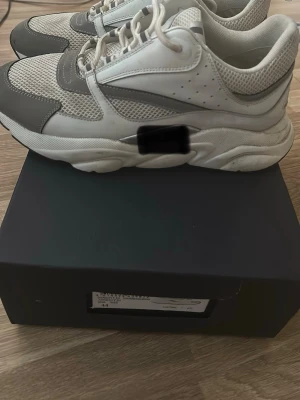 Chunky vita och grå sneakers - Snygga chunky sneakers i vitt och grått med meshpaneler och detaljer i läderimitation. Skorna har tjock sula och klassisk snörning. Perfekta för dig som gillar en sportig och trendig look.