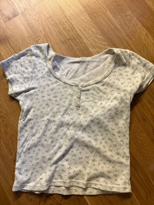 Brandy Melville T-shirt  - Blommig T-shirt ifrån Brandy Melville med gulliga detaljer 