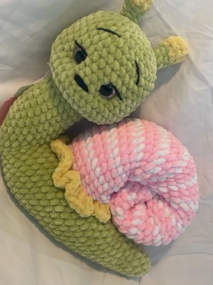 Mysig snigel mjukisdjur grön rosa - Supergullig snigel som mjukisdjur i grönt, rosa och vitt plyschmaterial. Snigeln har stora säkerhets ögon, gula detaljer och ett snurrat skal. Perfekt som present eller dekoration i rummet. 23cm