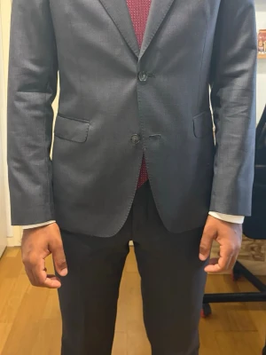 Oscar Jacobson kostym  - Oscar Jacobson kostym 100% ull, mörkgrå.  Personen i bilden är 180cm 77kg och byxorna sister tight.  (slips och skjorta ingår ej!)  Ny pris 6000kr