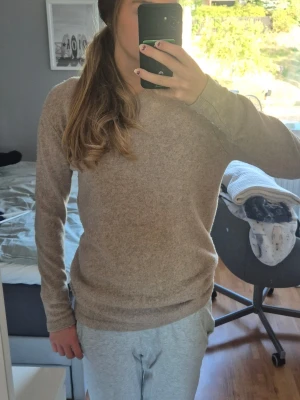 Beige stickad tröja  - Mysig beige stickad tröja med rund halsringning och långa ärmar. Tröjan har en enkel, klassisk design och ribbstickade muddar vid ärmslut och nederkant. Perfekt för hösten som kommer och passar till det mesta i garderoben. Tröjan har ett litet hål på framsidan (kolla bild), men är inget som syns när tröjan är på. Tröjan är köpt för 400 kr. Skriv för fler frågor 🌸