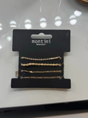 Guldiga armband från Montini - Snyggt set med fyra guldiga armband från Montini. Ett armband har glittrande pärlor, medan de andra har olika kedjedesigner. Perfekt för att mixa och matcha till din stil. Alla armband har justerbara länkar för bästa passform.