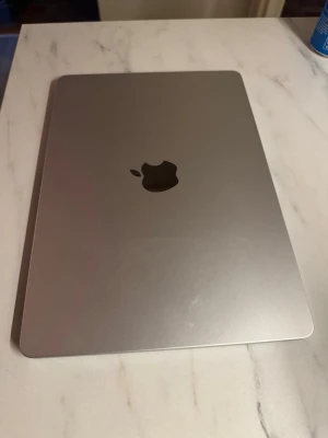 Apple MacBook M4 - Snygg och stilren MacBook i silver med aluminiumchassi. Tangentbordet har bakgrundsbelysning och skärmen har tunna kanter. Perfekt för studier, jobb eller kreativt skapande. Klassisk Apple-design med logga på locket.