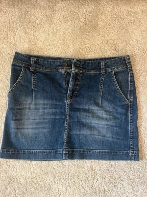 Jeanskjol  - Säljer en klassisk blå jeanskjol från White Stuff. Kjolen har normal passform, bälteshällor och två framfickor. Perfekt till vardags och enkel att matcha med olika toppar. Gjord i slitstarkt denimtyg.