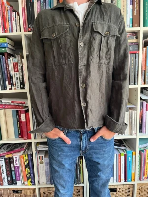 Olivgrön overshirt med bröstfickor - Snygg olivgrön overshirt från bondelid i avslappnad passform med två stora bröstfickor med lock och knapp. Den är i linne och passar perfekt nu till hösten om man vill ha något över hoodien