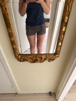 Gröna lågmidjade shorts med knappar från Bershka  - Snygga gröna shorts med låg midja och dekorativa knappar framtill. Shortsen har också en dragkedja i sidan. 