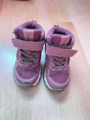Rosa kängor från Everest barn storlek 25 - Säljer ett par rosa kängor från Everest med kardborreband och elastiska skosnören. Skorna har en robust sula med bra grepp och meshdetaljer på sidorna för extra ventilation. Perfekta för utomhusaktiviteter och har en sportig look. Vattentäta.