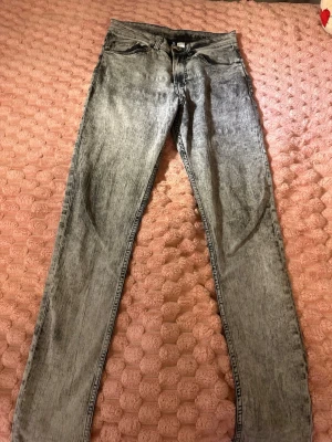Grå skinny jeans med tvättad look - Säljer ett par grå skinny jeans med tvättad, lite sliten look. Jeansen har klassisk femficksmodell, knappgylf och smala ben. Perfekta för dig som gillar en trendig och avslappnad stil.