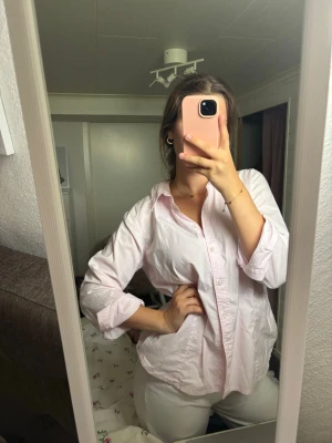 Ljusrosa oversized skjorta - Säljer en ljusrosa skjorta i oversized modell med klassisk krage och knappar framtill. Skjortan har långa ärmar och är tillverkad i ett mjukt bomullstyg. Perfekt för en avslappnad och trendig look.