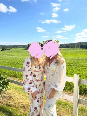 Vit långklänning med blommor - Vit långklänning med v-ringning och långa puffärmar.