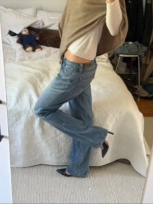 Blå Levis jeans med låg midja - Säljer ett par blå Levis jeans med låg midja och raka/utsvängda ben. Jeansen har klassiska fem fickor och en avslappnad passform. Perfekta till sneakers eller klackar för en cool och avslappnad look.