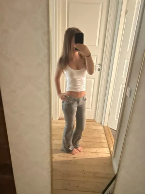 Ljusgrå bootcut jeans - Säljer ett par ljusgrå bootcut jeans med låg midja och klassisk femficksdesign. Jeansen har en snygg tvätt och sitter tajt över höfterna för en trendig look. Perfekta till en enkel topp eller hoodie.