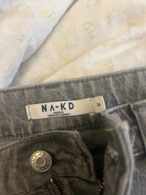 Gråa raka jeans från NA-KD - Säljer ett par gråa jeans från NA-KD i storlek 34. Jeansen har en rak passform med klassisk femficksdesign och normalhög midja. Materialet är mjukt denim som sitter snyggt och bekvämt. Perfekta till en avslappnad look.