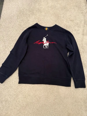Polo Ralph Lauren Sweatshirt  (Stl L 14-16 / XS) - Snygg mörkblå crewneck från Polo Ralph Lauren med stor vit Big Pony och röd broderad signatur på bröstet. Riktigt fräsch modell 