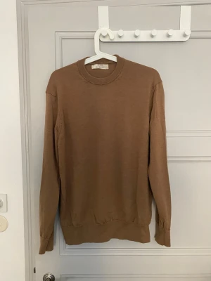 Beige stickad tröja från Zara Origins - Snygg beige stickad tröja från Zara Origins i storlek M. Tröjan har rund halsringning, långa ärmar och ribbade muddar vid ärmslut och nederkant. Perfekt för lager på lager och enkel att matcha med olika outfits.