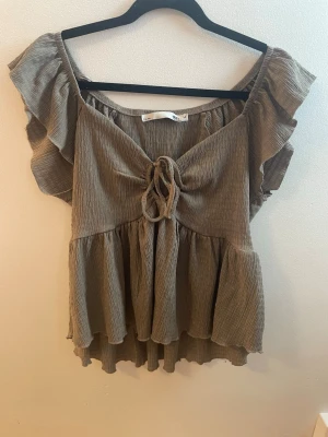 Beige top med volanger  - Beige topp med volanger i storlek M från Lager 157 