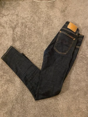 Mörkblå slim fit jeans - Tja säljer ett par snygga jeans ifrån nudie. Det är i en mörkblå färg. Jeansen är i slim fit och sitter väldigt skönt. Vid minsta fundering är det bara att höra av er. 