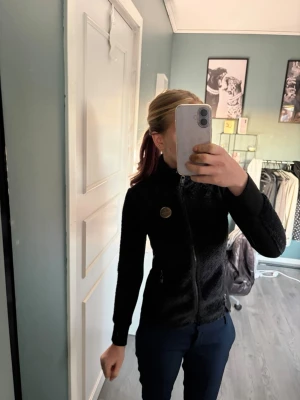 Svart teddyjacka med dragkedja - Snygg svart teddytröja från JH collection med mjuk, fluffig yta och hög krage. Jackan har hel dragkedja framtill. Perfekt för kyliga dagar i stallet. Säljer då den är för liten för mig. Pris kan diskuteras vid snabbt köp💕