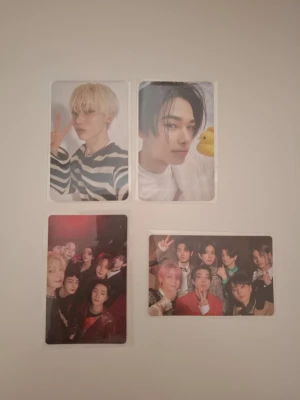 Fyra K-pop photocards - Säljer ett set med fyra K-pop photocard med färgglada porträtt och gruppbilder. Två kort har närbilder på medlemmar med olika frisyrer och outfits, och två kort visar hela gruppen i olika poser. Perfekt för samlare eller fans av K-pop. Materialet är glansig plast.