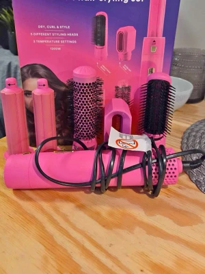 Rosa multifunktionell hårstyler - Säljer en rosa multifunktionell hårstyler med fem olika stylinghuvuden, inklusive rundborste, värmeborste och locktillbehör. Aldrig använt. Perfekt för att skapa olika frisyrer med tre temperaturinställningar. Allt i snygg och färgstark design.