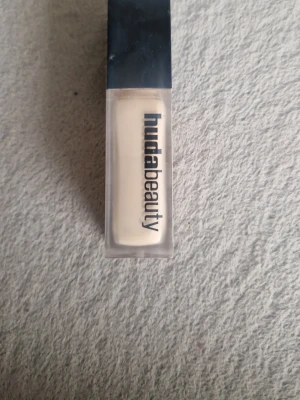 Huda Beauty FauxFilter Concealer - Flytande concealer från Huda Beauty i nyansen Marshmallow 1.3G. Ger en matt men ändå lystergivande finish. Kommer i en rektangulär plastförpackning med svart lock och tydlig logga. Perfekt för att täcka mörka ringar och ojämnheter.obs den är använd men färgen passar inte mig 