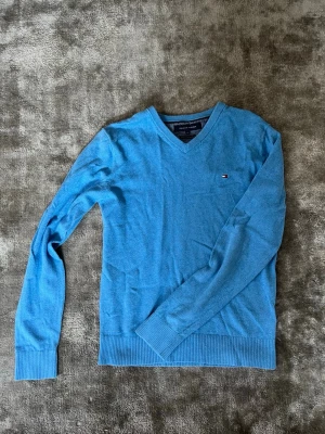 Blå stickad tröja Tommy Hilfiger - Snygg blå stickad tröja från Tommy Hilfiger med V-ringning och diskret logga på bröstet. Tröjan har långa ärmar och ribbade muddar vid ärmslut och nederkant. Perfekt att matcha med jeans eller chinos. Passar riktigt bra under en skjorta eller till bara jeans. Om du har frågar är det bara att fråga på. Pris går att diskutera med seriösa köpare. Kolla in min profil och se om du hittar något mer intressant. Mvh Larsen_Closet