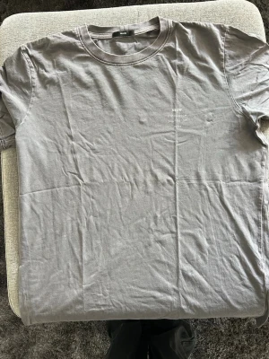 Grå t-shirt från Neuw - Snygg grå t-shirt från Neuw med diskret tryck på bröstet där det står 'NEUW STOCKHOLM MELBOURNE 2009'. Klassisk rund halsringning och korta ärmar. Tillverkad i mjuk bomull som känns skön mot huden.