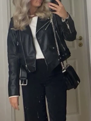 Svart skinnjacka med dragkedjor - Säljer en svart skinnjacka från Zara med coola silvriga dragkedjor och detaljer. Jackan har klassisk bikerstil med bred krage. 