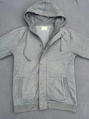 Unik cardigan / hoodie - Riktigt snygg hoodie / cardigan med både knappar och zip. En clean stil och perfekt mot hösten. Storlek L men sitter som M. Fint skick.